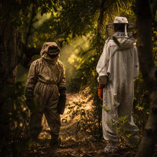 Wild honey hunters facing each other in dense forest during traditional raw honey harvesting expedition