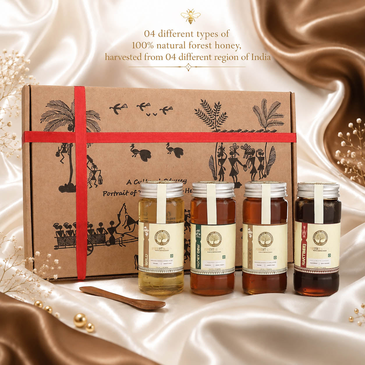 A gift set of four honey jars displayed in front of a brown illustrated cardboard box tied with a red ribbon. The set includes honey from different regions of India, with labels for Manjra, Khandala, Renuka, and Mandar.