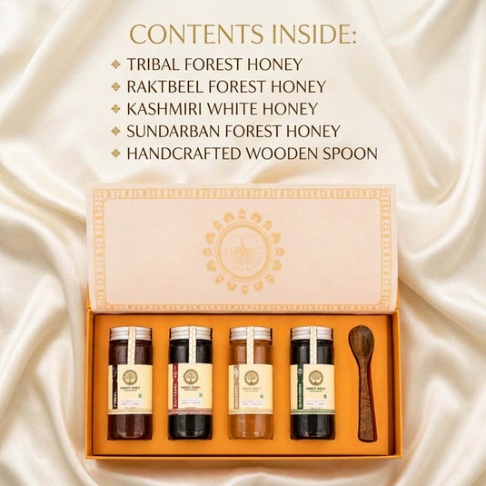 An open gift box of four honey jars and a wooden spoon on a cream satin background, with text listing contents: tribal forest honey, rakteel forest honey, Kashmiri white honey, sundarban forest honey, and a handcrafted wooden spoon.
